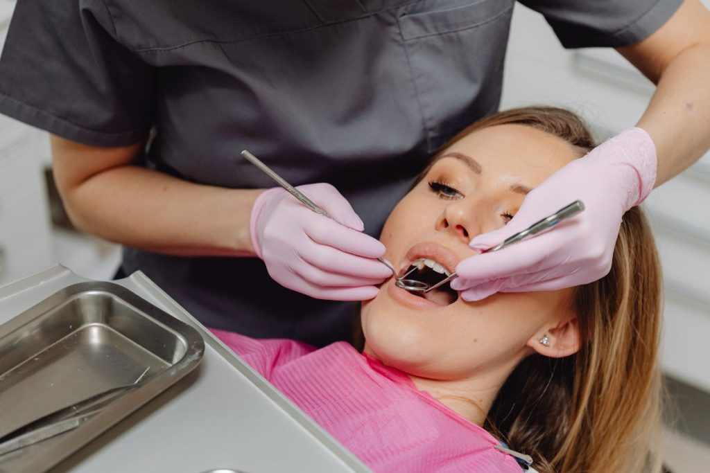 Dental professional performing an oral examination on a patient, showcasing modern cosmetic dentistry techniques and patient care at NuSmile Implant Studio.
