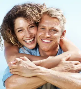 Happy couple embracing and smiling, showcasing confidence and joy, relevant to NuSmile Implant Studio's focus on enhancing patient smiles and oral health.